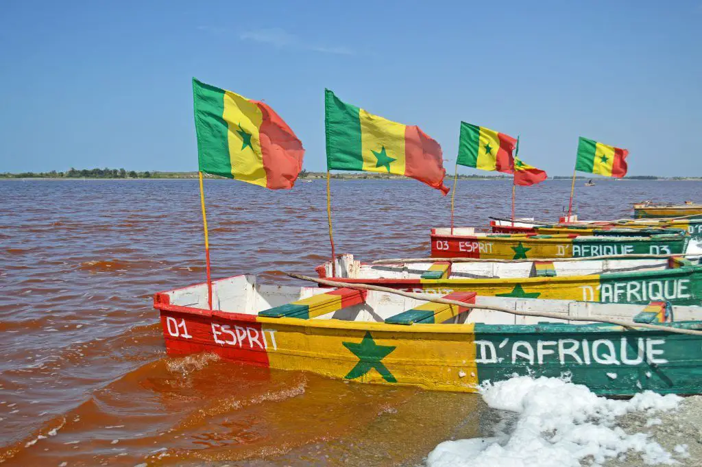 Barcas con la bandera de Senegal en el lago rosado o lago retba cercano a Dakar